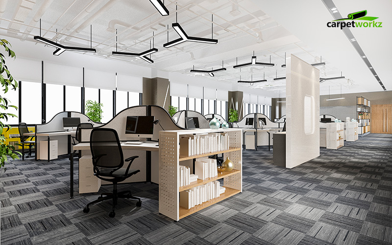 Bright open-plan office with patterned grey carpet tiles, modern workstations, and bookshelves