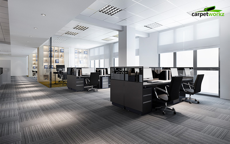 Office with grey carpet tiles, black desks, and big windows