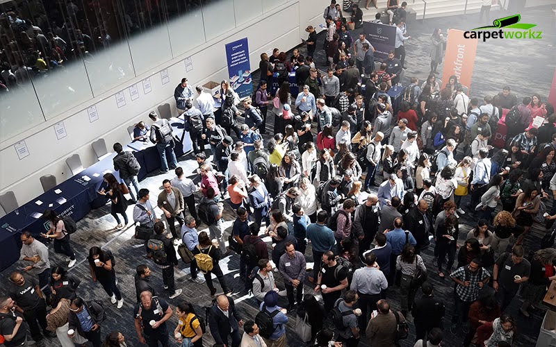 A large crowd gathers at a busy indoor event or expo