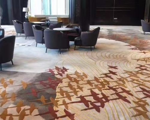 A room with chairs and a large blue and white hand tufted carpet with flower design.